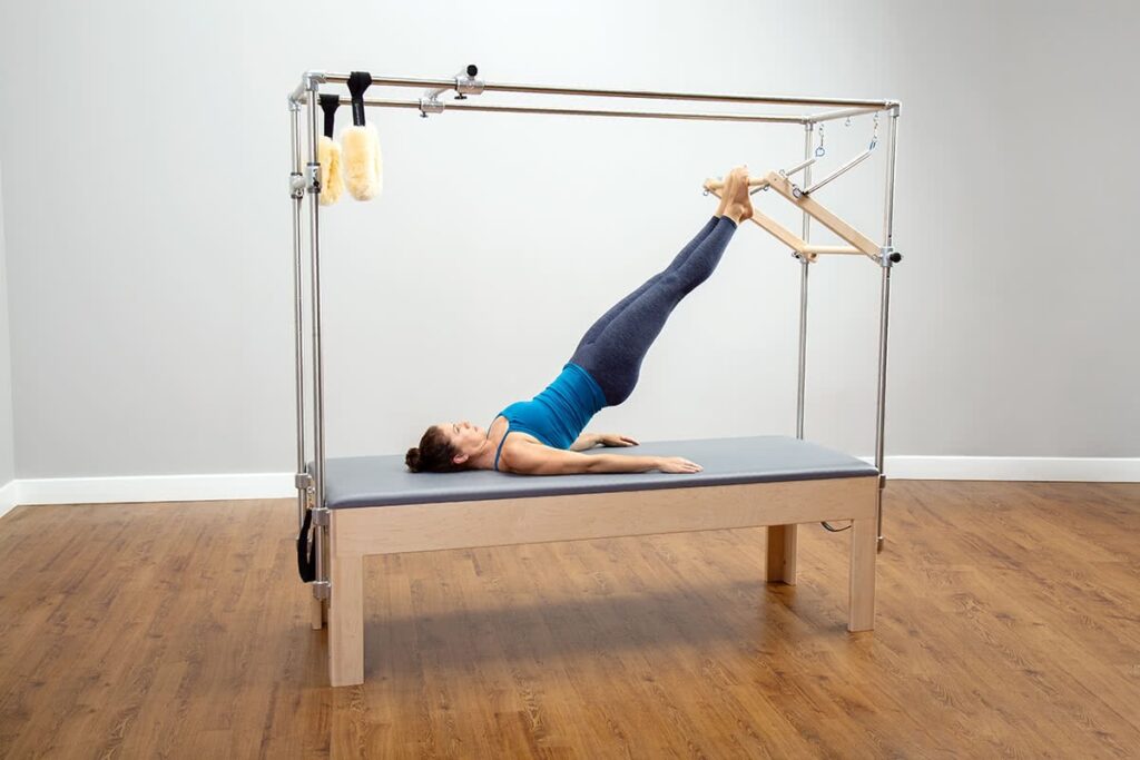 Pilates exercise on CenterLine Cadillac with legs raised.