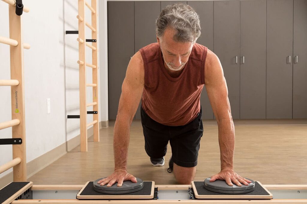 Vyras atlieka lentos pratimą su CoreAlign Pilates studijoje