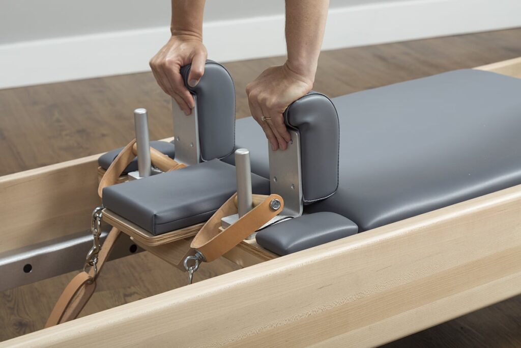Hands adjusting handles on CenterLine Reformer by Balanced Body.
