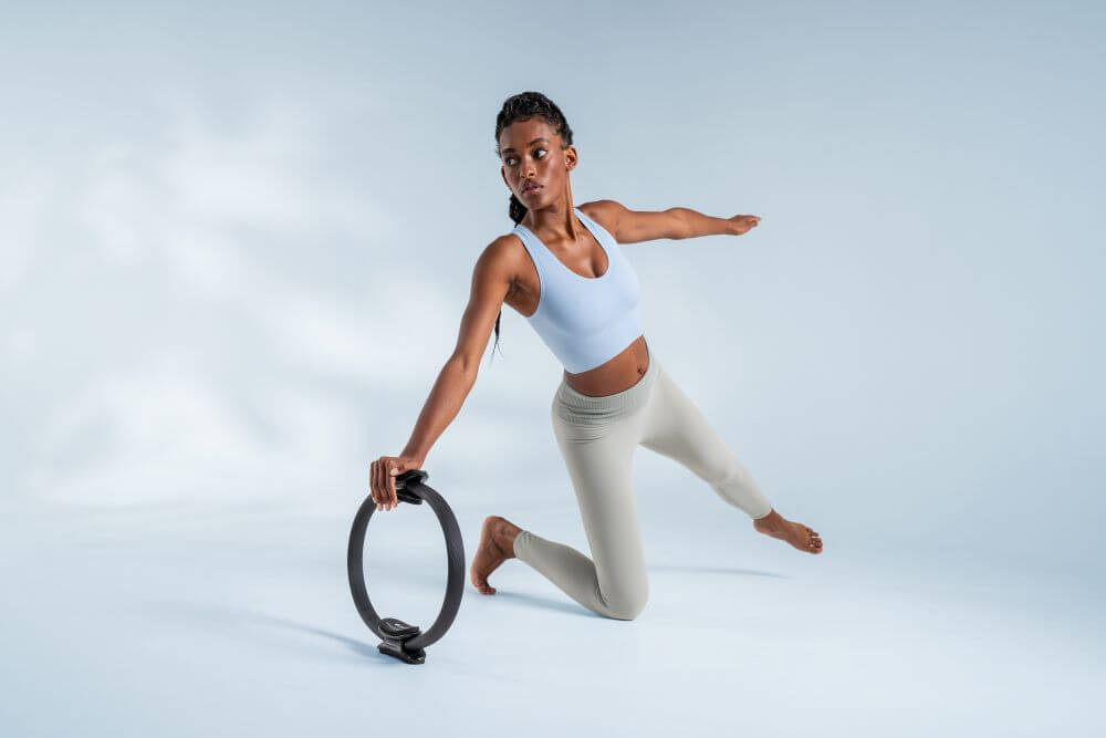 Moteris demonstruoja pilateso pratimą su Ultra-Fit ratu.