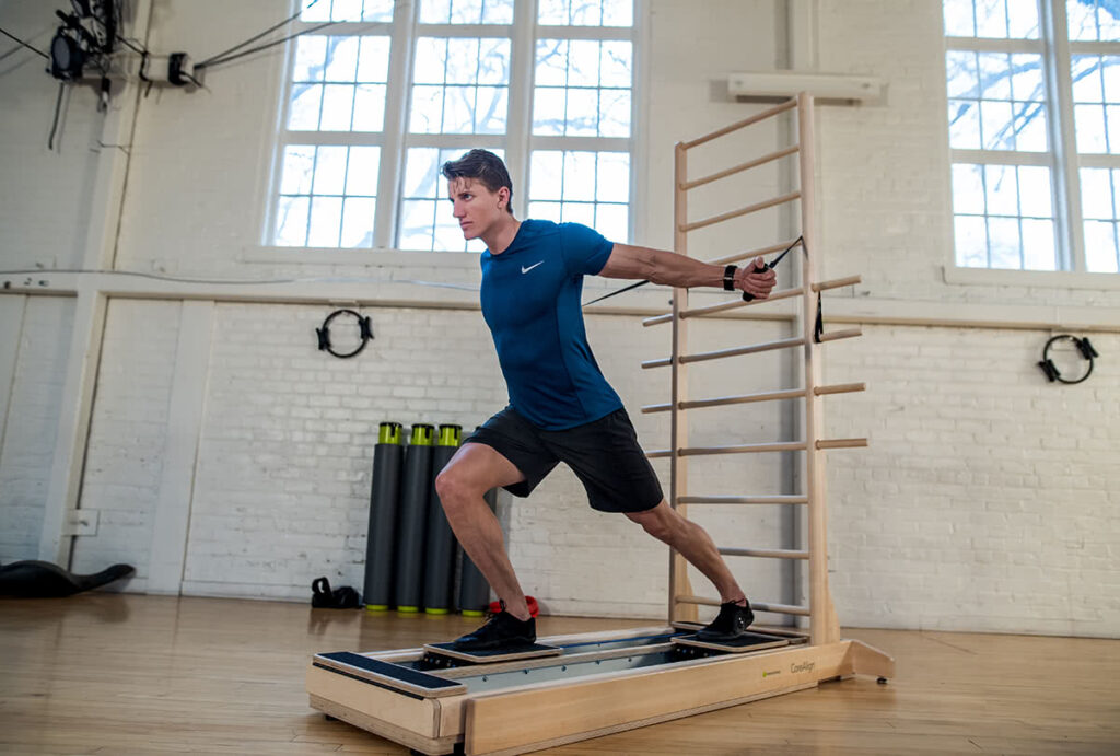 Vyras atlieka pratimą su CoreAlign ir sienine kopėtėle studijoje.