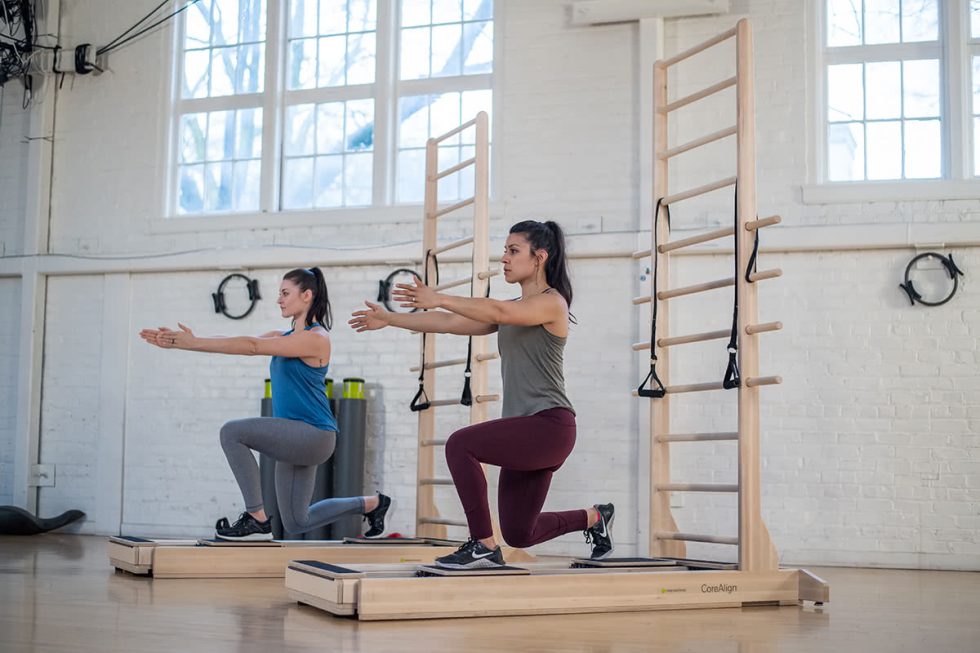 Dvi moterys atlieka pratimus su CoreAlign ir kopėtėlėmis studijoje.