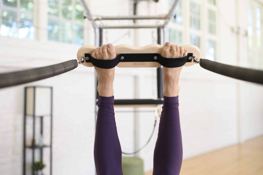 Пользователь выполняет упражнение на трапециевидном турнике тренажёра Кадиллак Contrology