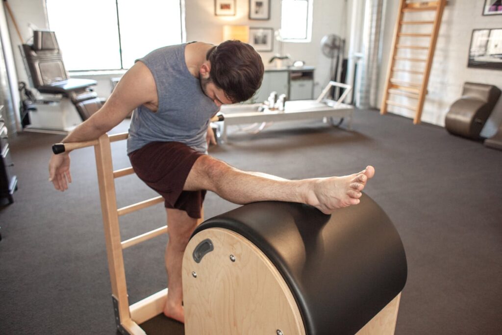 Man stretching on Contrology Ladder Barrel in Pilates studio.