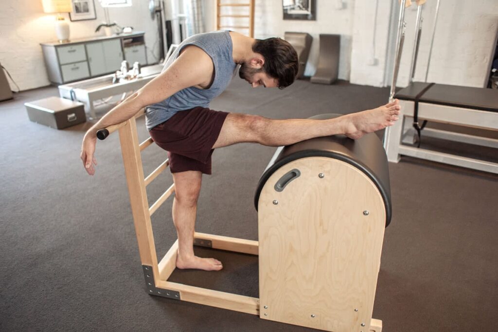 Instructor stretching on Contrology Ladder Barrel in studio.