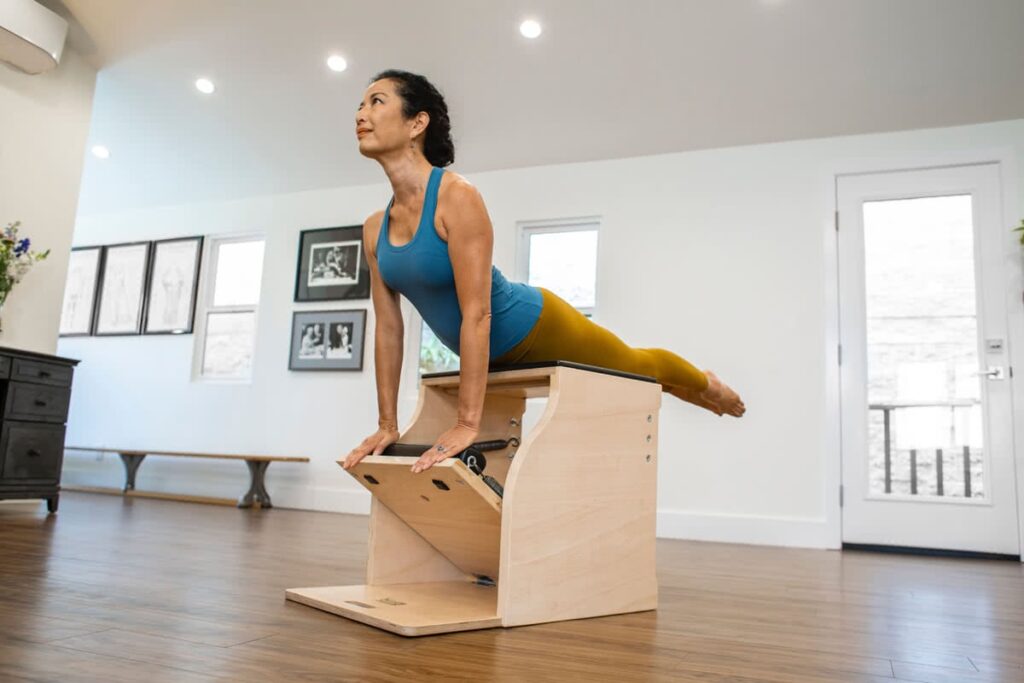 Woman exercising on Contrology Wunda Chair in a Pilates studio.
