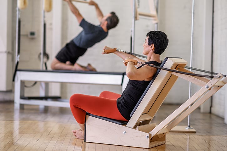 Asmuo sportuoja su Contrology rankų kėde Pilateso studijoje.