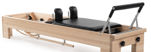 Pilates machine with two-position footbar and spring attachment system.