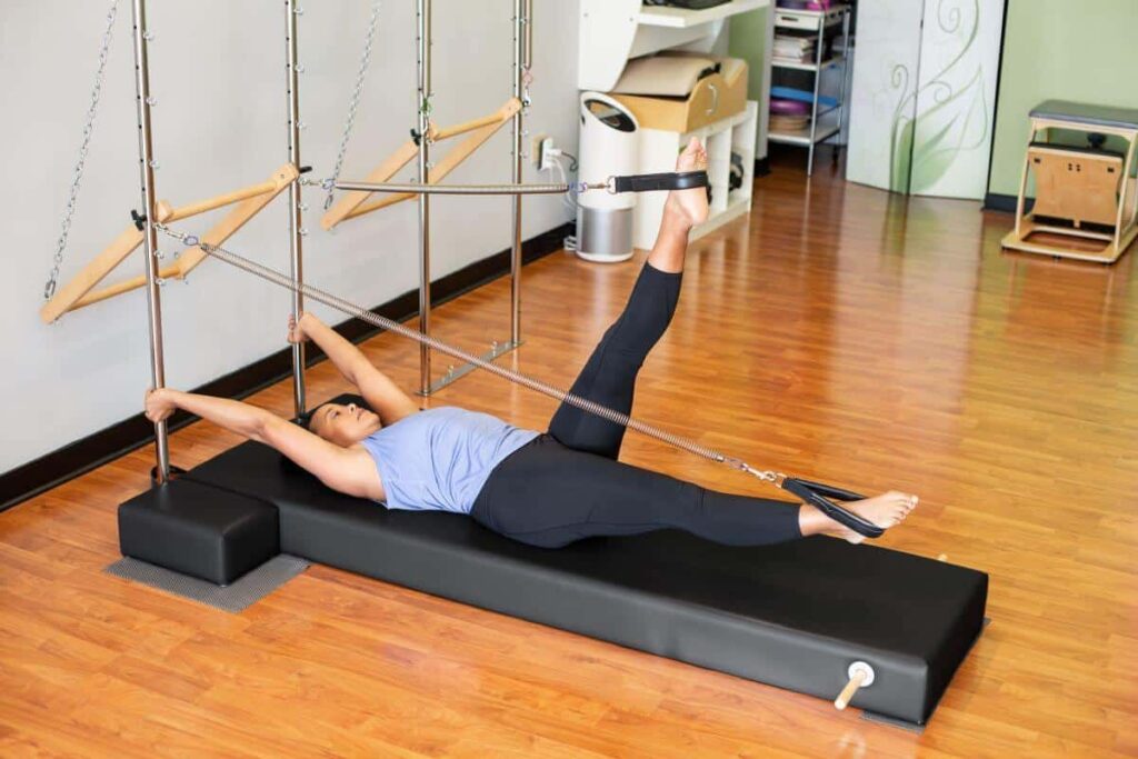 Asmuo naudoja CenterLine stulpų sistemą Pilates pratimams.