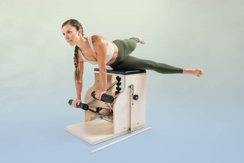 Woman exercising on Balanced Body Combo Chair for muscle strengthening.