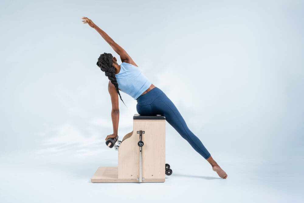 Person stretching on Balanced Body Combo Chair Pilates equipment.