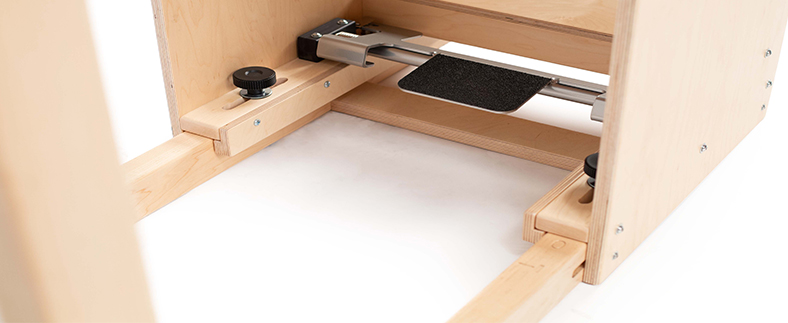 Pilates barrel with foot pedal for distance adjustment on ladder.