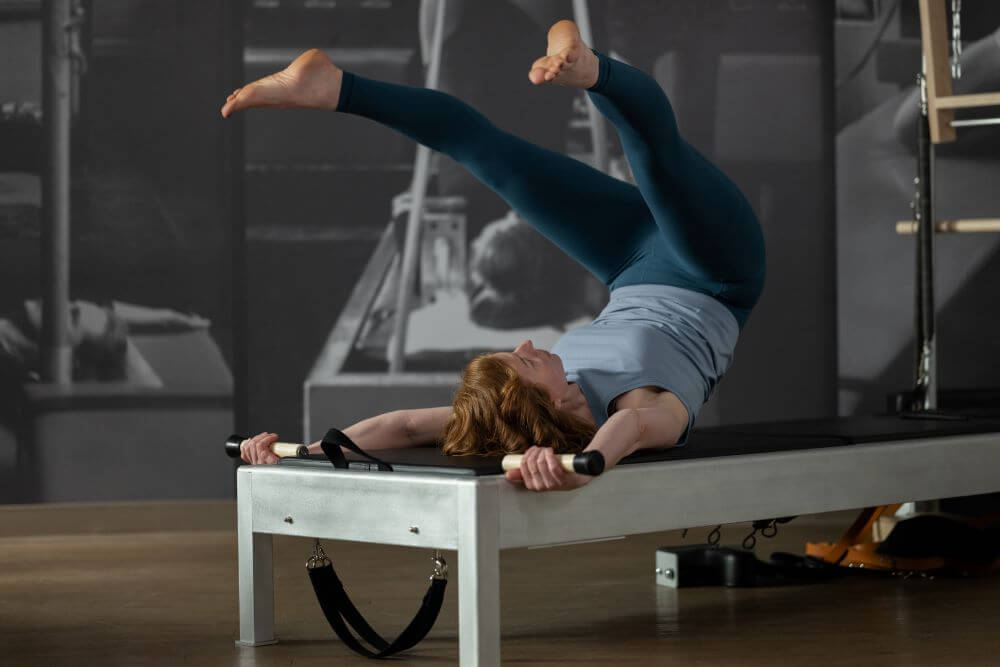 Женщина занимается на тренажёре Contrology Reformer с башней и ковриком