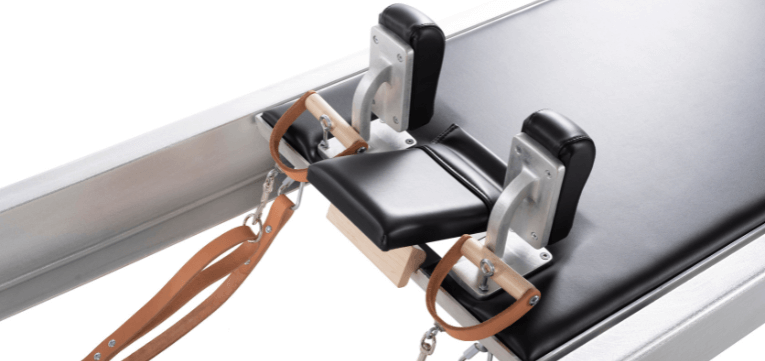 Коляска для пилатеса с черной обивкой и деревянным фиксатором подголовника.