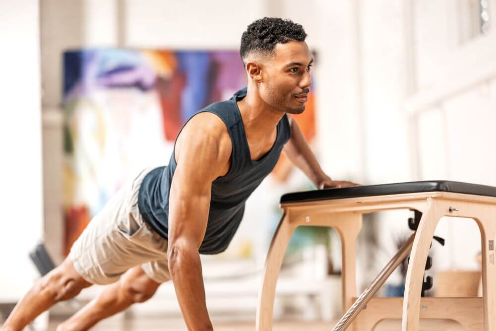 Мужчина занимается на тренажёре Pilates EXO Chair для тренировки всего тела