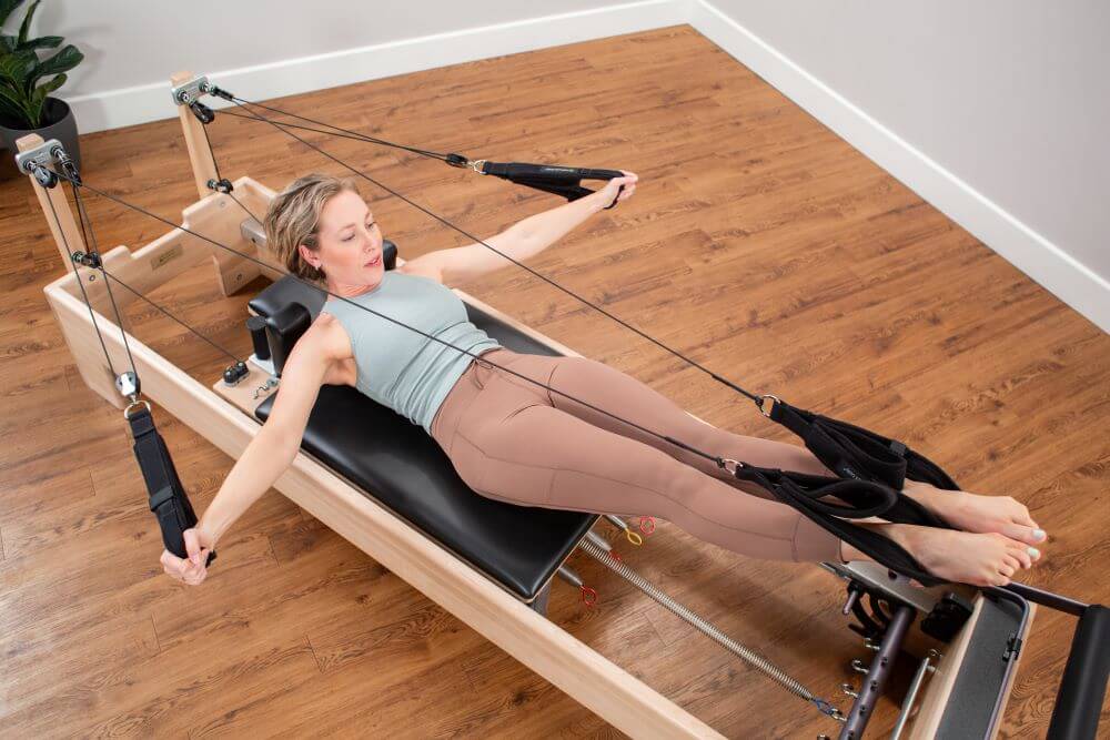 Woman exercising on Studio Reformer Konnector by Balanced Body.