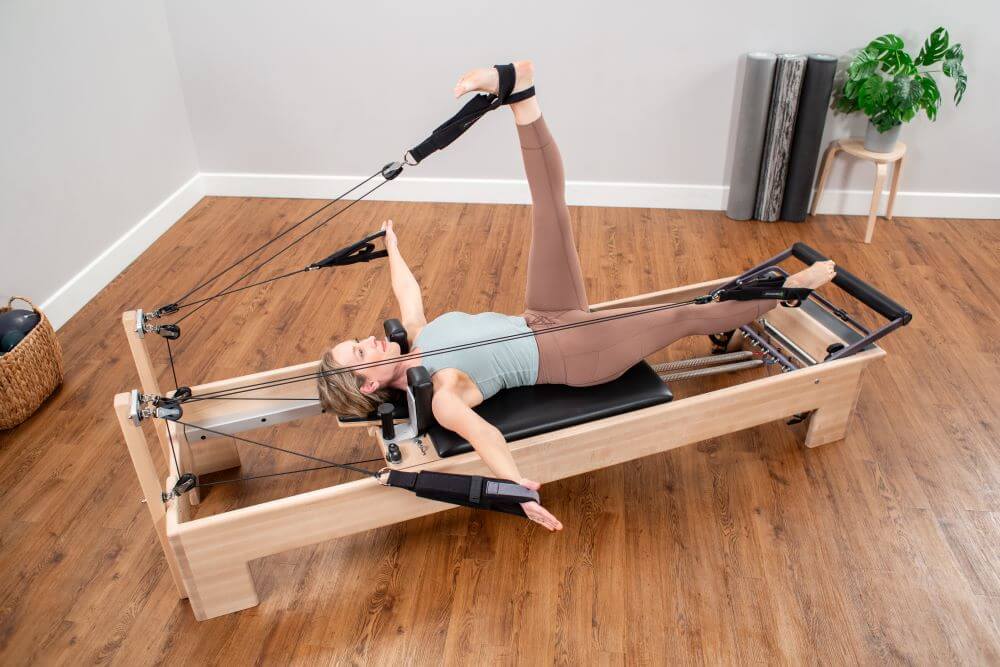 Person exercising on Studio Reformer Konnector with leg raised.