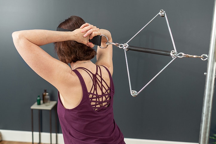 Asmuo demonstruoja Contrology kaklo tempiklį ant Cadillac treniruoklio.