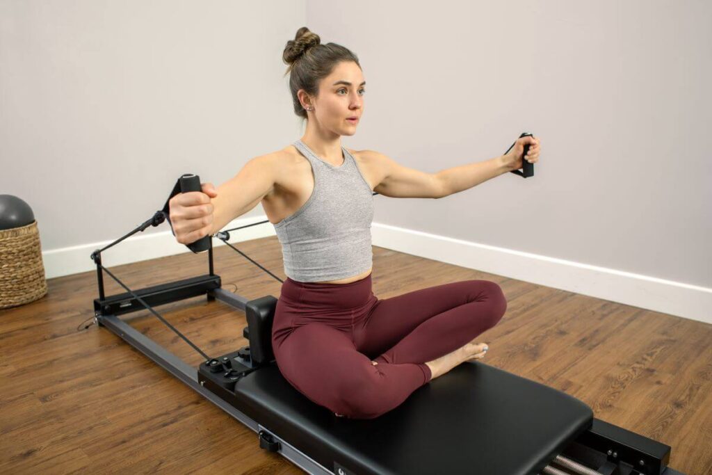Asmuo naudoja neopreno rankenas ant „Balanced Body“ pilateso treniruoklio.