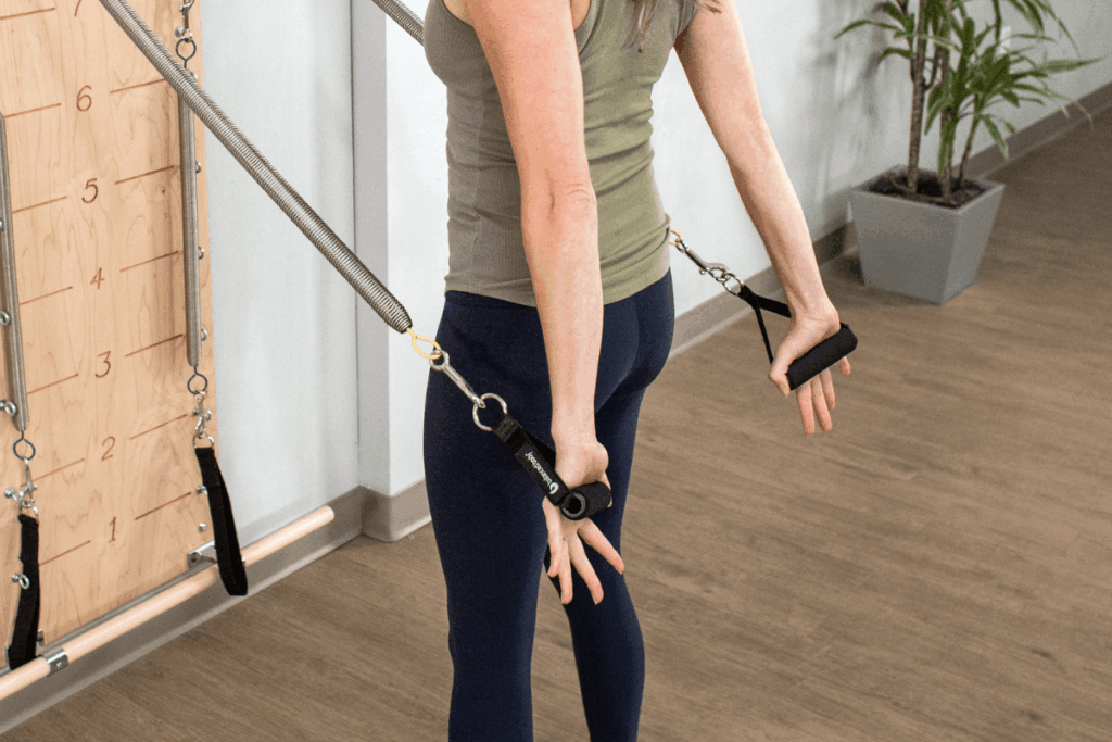 Asmuo naudoja Balanced Body neopreno rankenas Pilates treniruotėje.