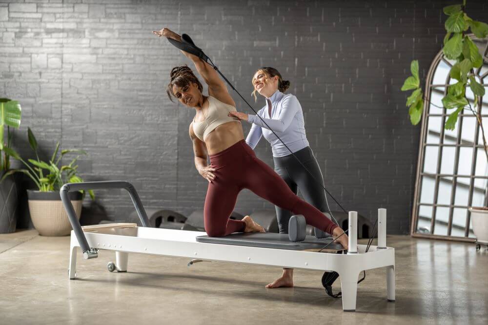 Pilates instructor assisting student on Allegro 2 Reformer.