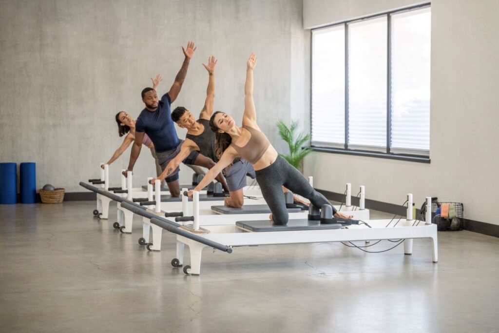 Fitneso entuziastai naudoja Allegro 2 Reformer Plank Bars studijoje.
