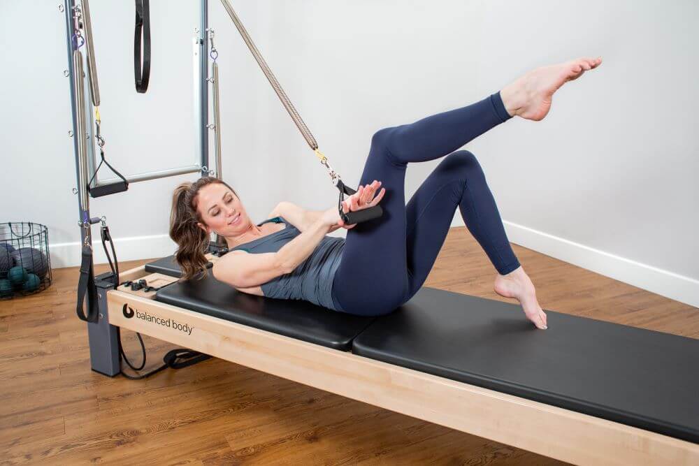 Woman exercising on Rialto Reformer with Tower in studio.