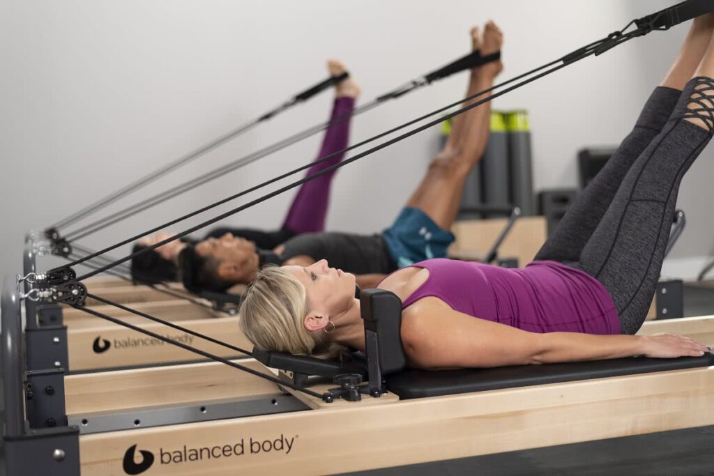 Pilates grupė studijoje naudoja Rialto Reformer treniruoklius.