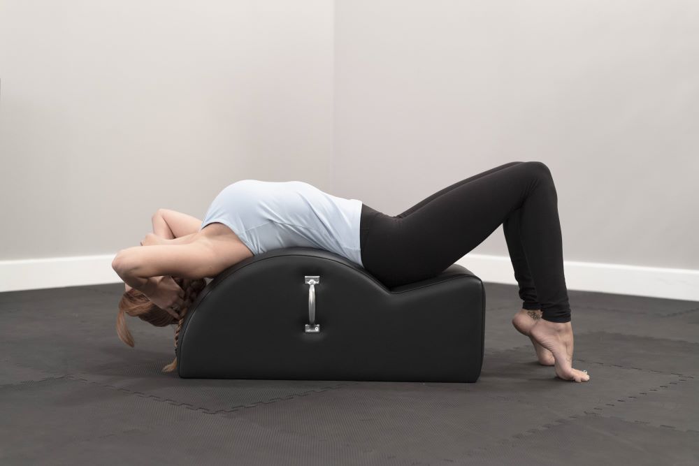 Person using East Coast Step Barrel for Pilates stretching exercise.