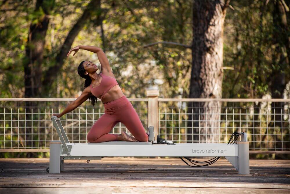 Pilates pratimas su Bravo Reformer lauko aplinkoje.