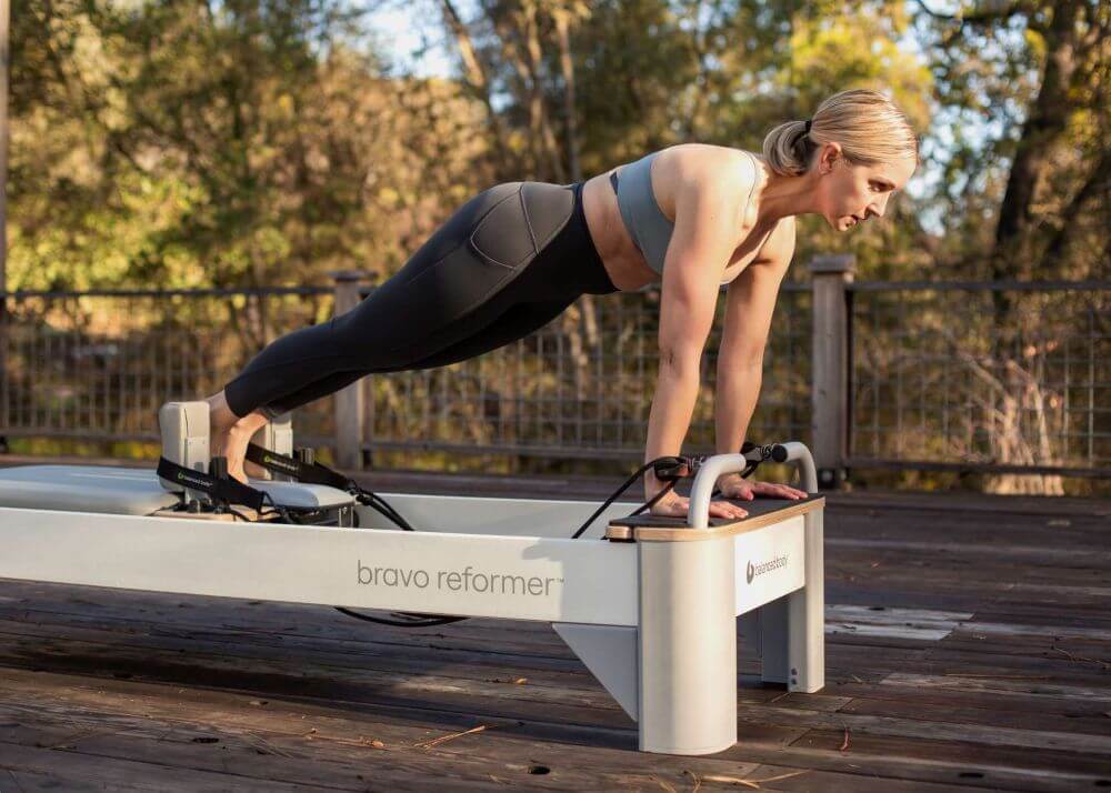 Asmuo praktikuojasi lauke ant Bravo Reformer Extended Head End Platform.